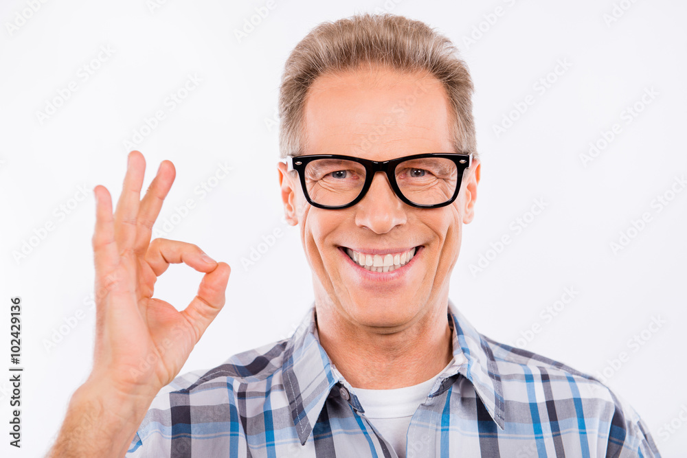 Handsome happy aged man in glasses gesturing ok