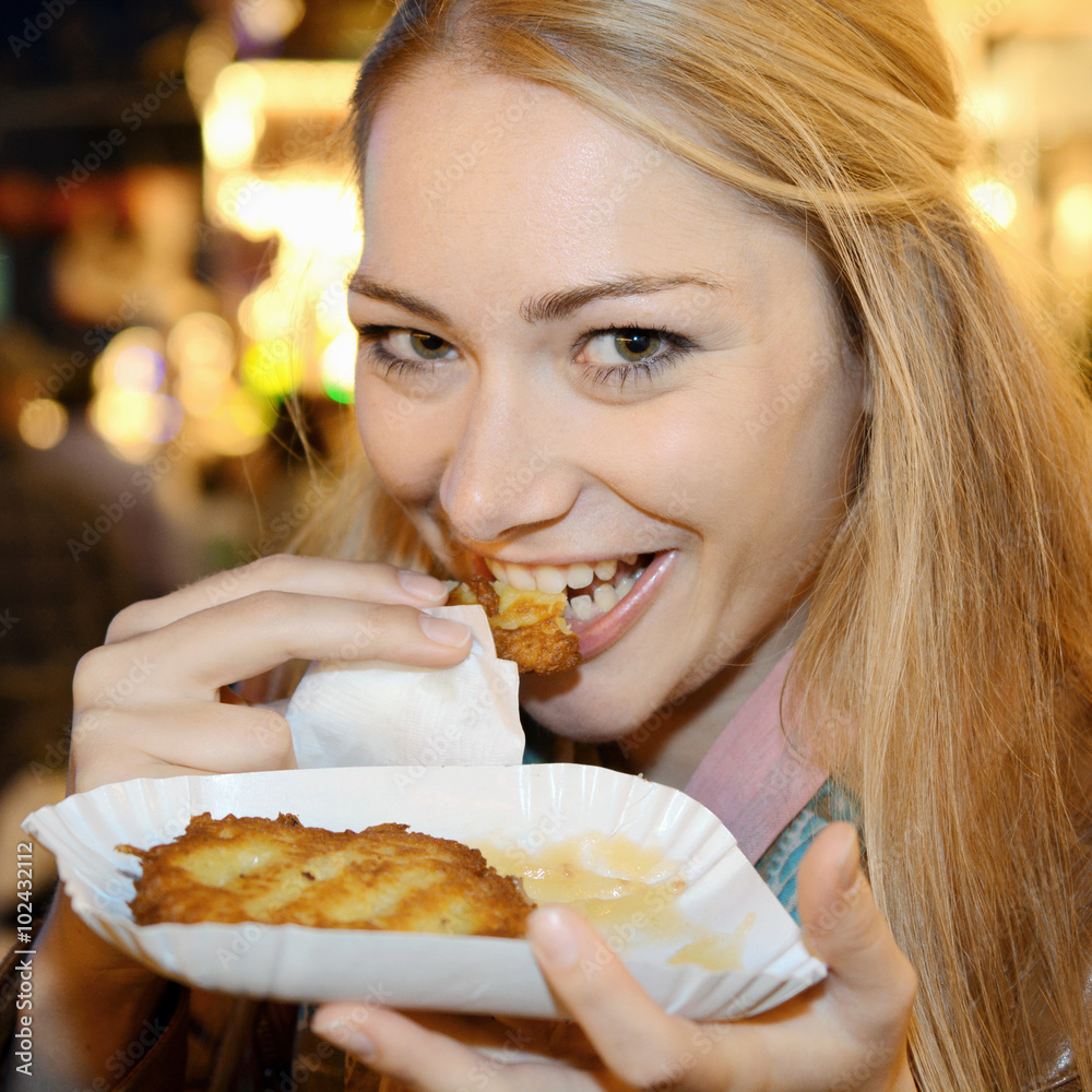 Frau isst Reibekuchen oder Kartoffelpuffer auf Jahrmarkt oder Kirmes
