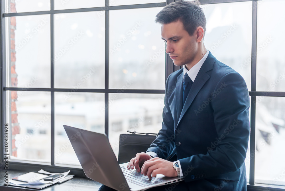 Businessman working on his laptop computer sitting in office
