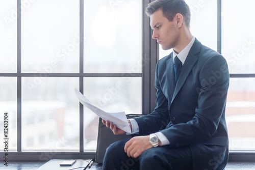 Businessman sitting in office reading contract documents