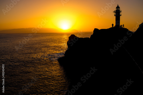 Rocky coastline with lighthouse on the sunset