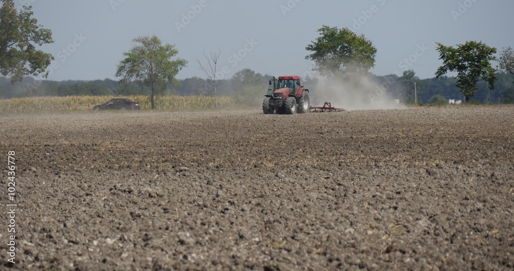 Tractor Distantly is Plowing The Field Tractor is Approaching Flying Dust Behind the Tractor Road along the Field Cars on the Road Trees along Road Tractor Distantly is Plowing The Field Tractor is Approaching Flying Dust Behind the Tractor Road along the Field Cars on the Road Trees along Road