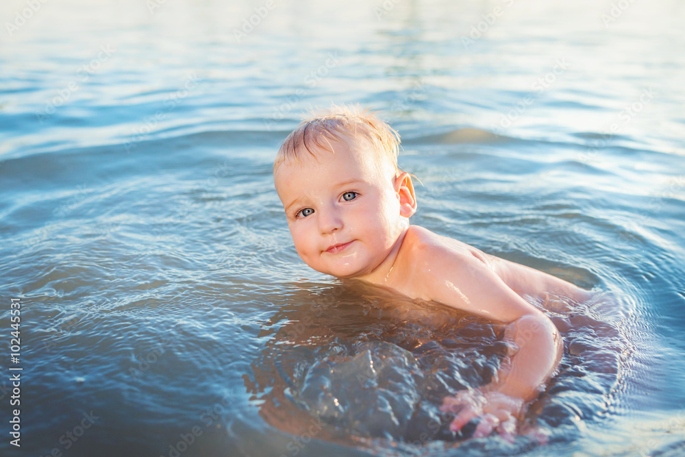 Little boy swimming in the water on sunny summer day