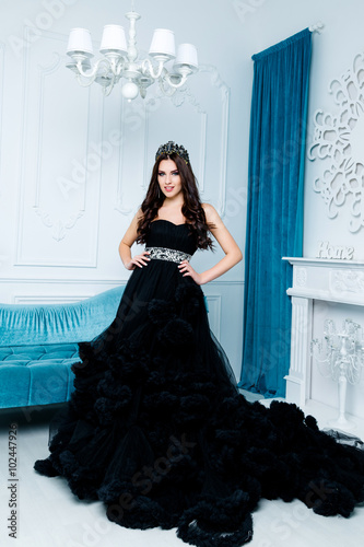 Fashion shoot of beautiful woman in a long black dress in blue room