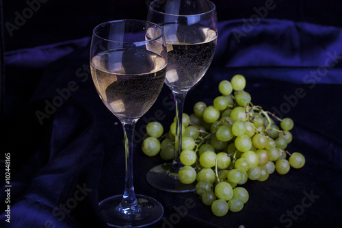 Glasses of wine and grapes on a dark background