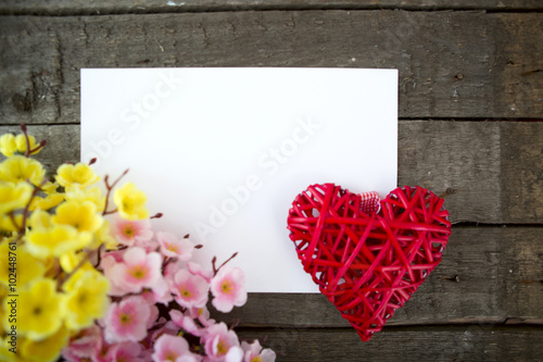 Flowers and heart shape note paper on wood background. photo