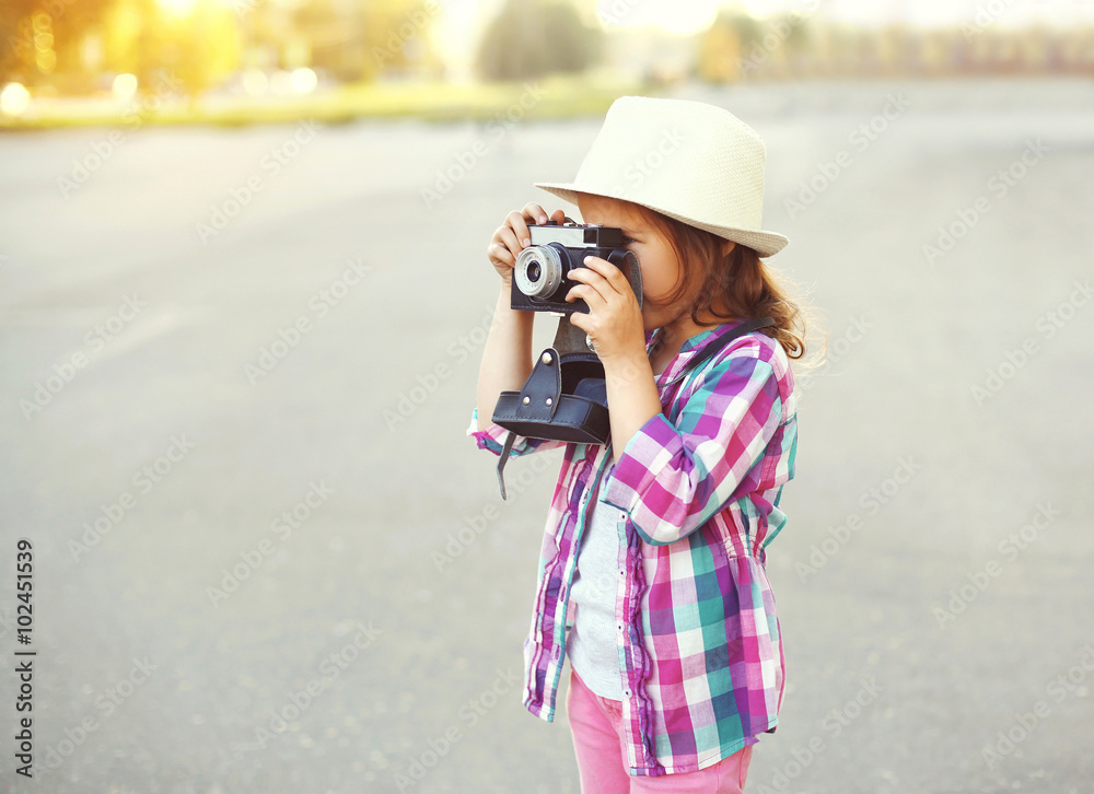 Little girl child with retro camera doing snapshot outdoors, pro