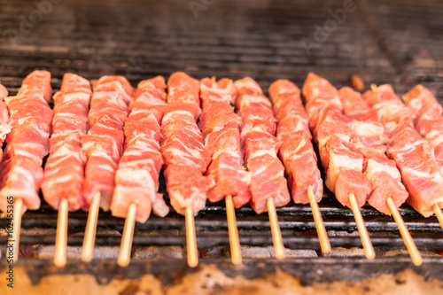 fresh raw red meat pork breast fillets on a skewer barbecue grill grid roasts.skewers of pork on a wooden stick. Greece, souvlaki.