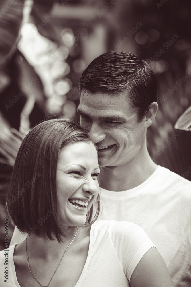 Black and white close-up portrait of two people couple, Caucasian man woman girl together, standing in park outside, smiling laughing hugging, looking away, intimate moment of love, Valentines day