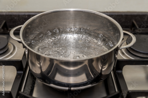 Metal cooking pan with boiling water on a stove
