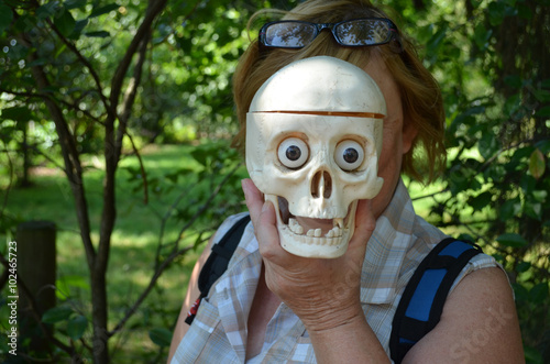 Woman holding a plastic skull in front of her face