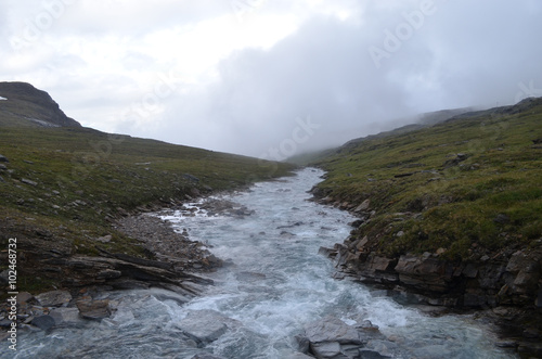 Rocky river flowing through tundra valley, subarctic mountains, Swedish Lapland