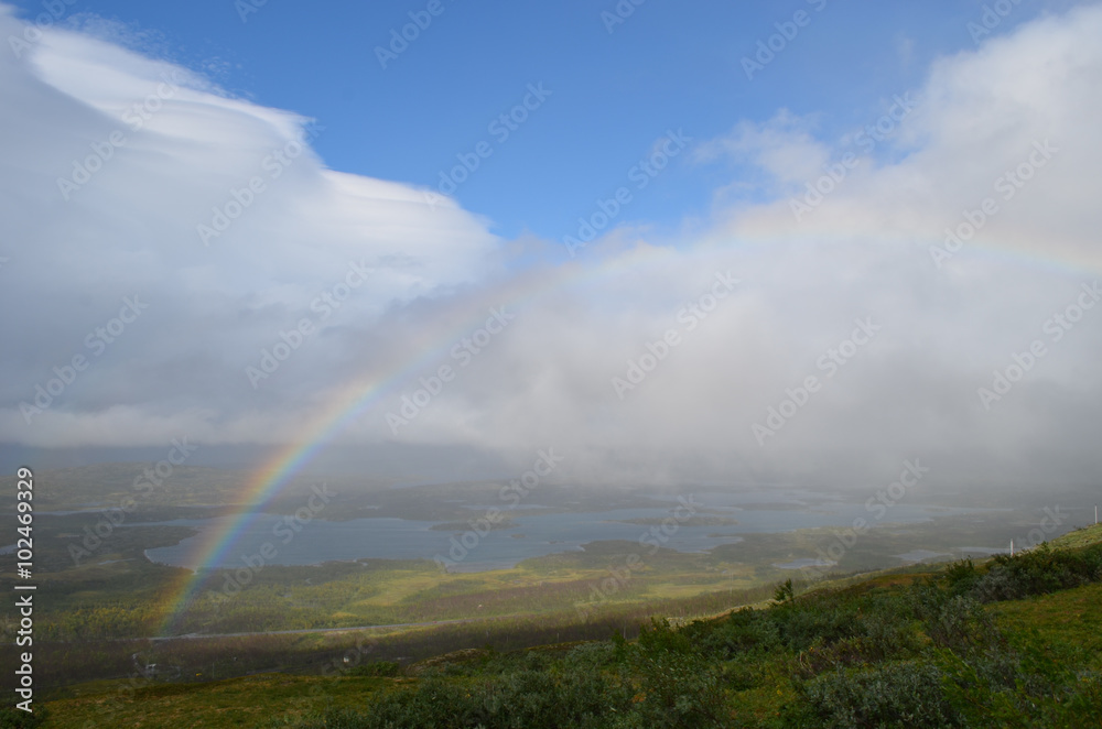 Clouds, rainbow and sunshine over valley in subarctic mountains, Swedish Lapland