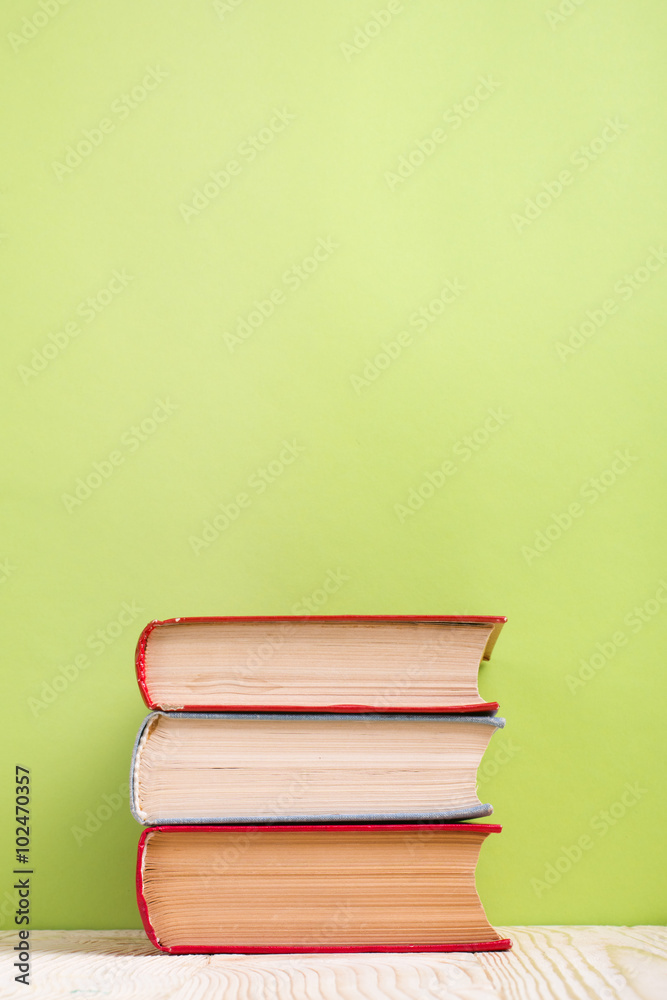Stack of hardback books, diary on wooden deck table and green background. Back to school. Copy Space. Education background Stack of hardback books, diary on wooden deck table and green background. Back to school. Copy Space. Education background