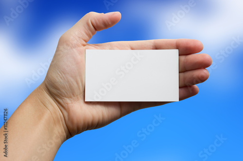 Hand holding white business card on blurred background