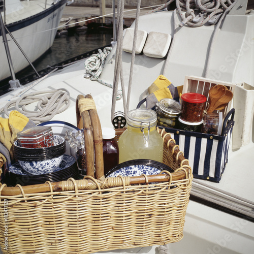 Food items with tableware in picnic basket on sailboat