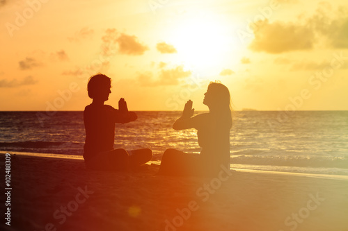 silhouette of couple doing yoga at sunset © nadezhda1906