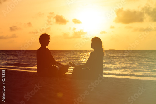 silhouette of couple doing yoga at sunset