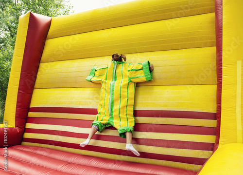 Young woman in plastic dress in a bouncy castle imitates the fly photo