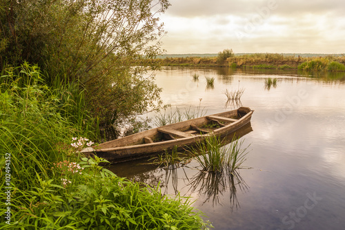 Old wooden boat near the shore of the river photo