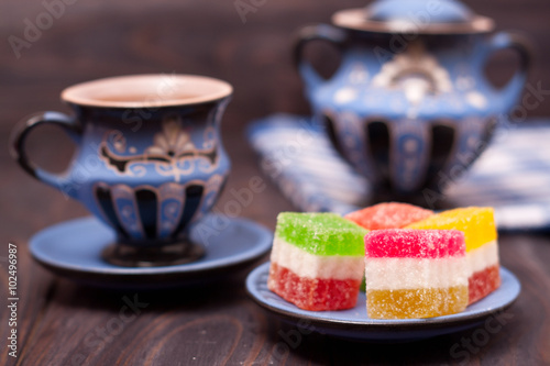 fruit jelly on wooden background with cup of tea