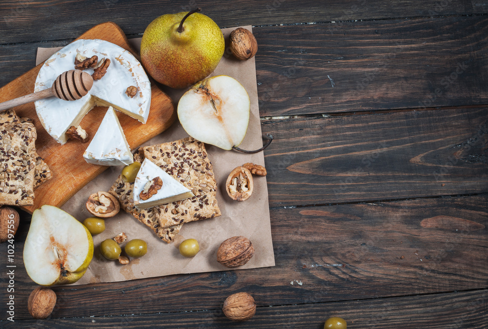 Camembert cheese with walnuts, honey and pears on rustic table. Glass of white wine Camembert cheese with walnuts, honey and pears on rustic table. Glass of white wine