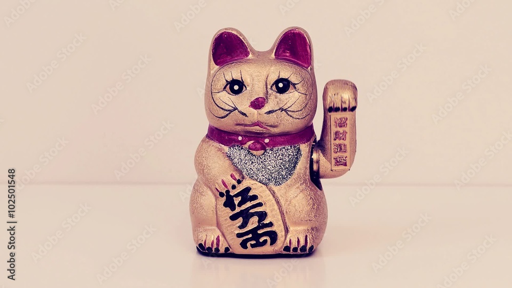 cinemagraph of a chinese lucky cat moving its left paw up and down ...