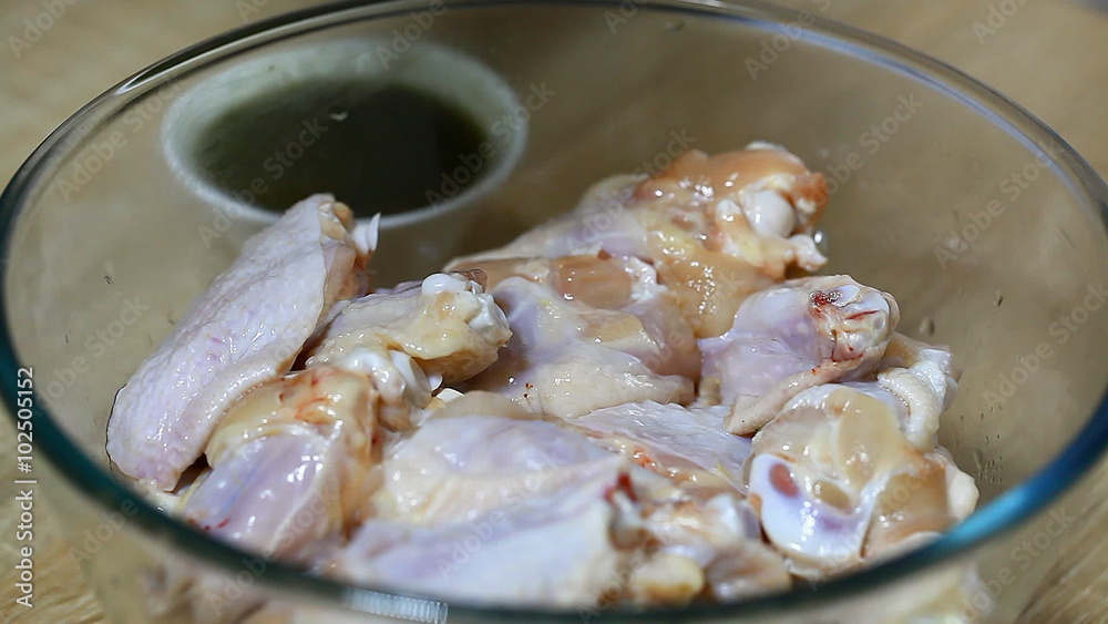 a cook pours marinade on chicken wings a cook pours marinade on chicken wings