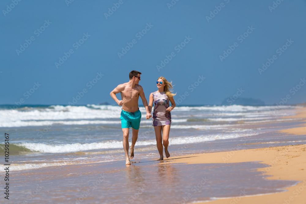 Couple Running Through Waves On Beach Holiday Couple Running Through Waves On Beach Holiday