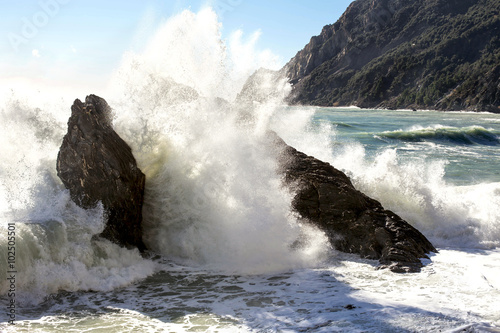waves crashing against big rocks to the beach