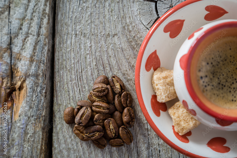 Fototapeta premium Coffee in white cup with hearts, beans, rustic wood background