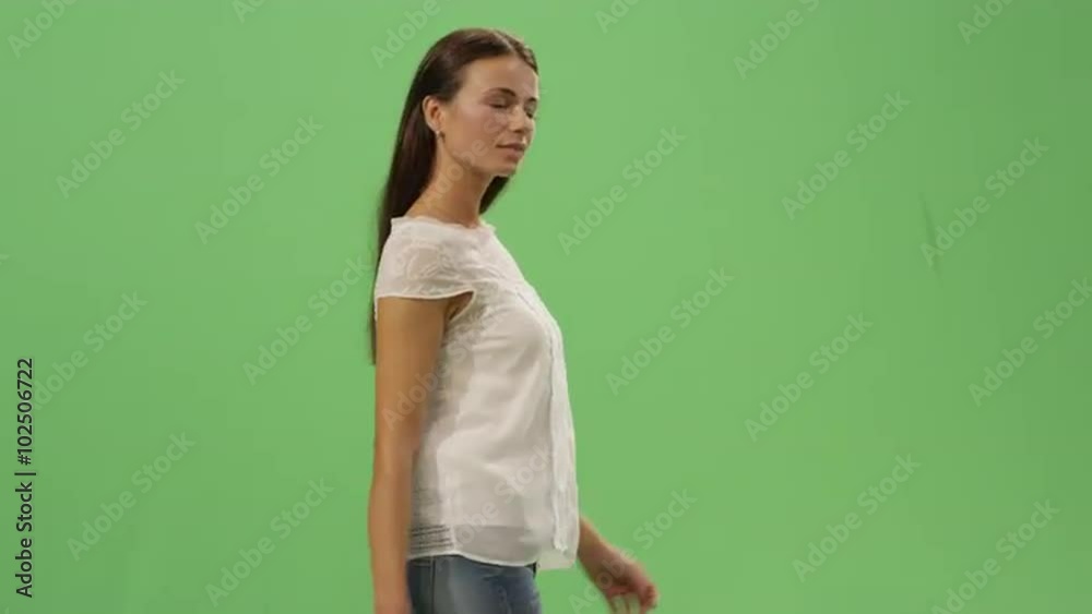 Casual young brunette girl is walking on a mock-up green screen in the background. Shot on RED Cinema Camera.
