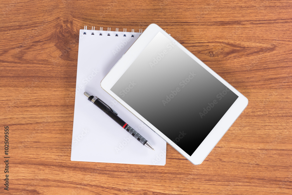 Tablet device on wooden workspace table Tablet device on wooden workspace table