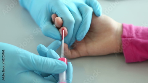 Nurse takes blood from a finger of child in medical laboratory.