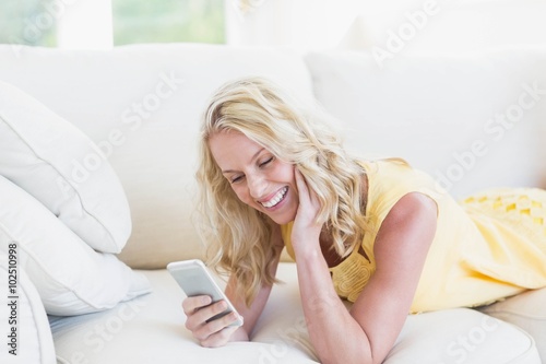 Happy woman using smartphone on the sofa