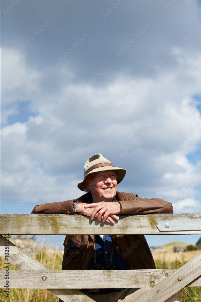 Senior Man On Walk Leaning Against Wooden Gate Senior Man On Walk Leaning Against Wooden Gate