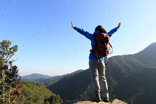 successful woman hiker open arms on sunrise mountain peak