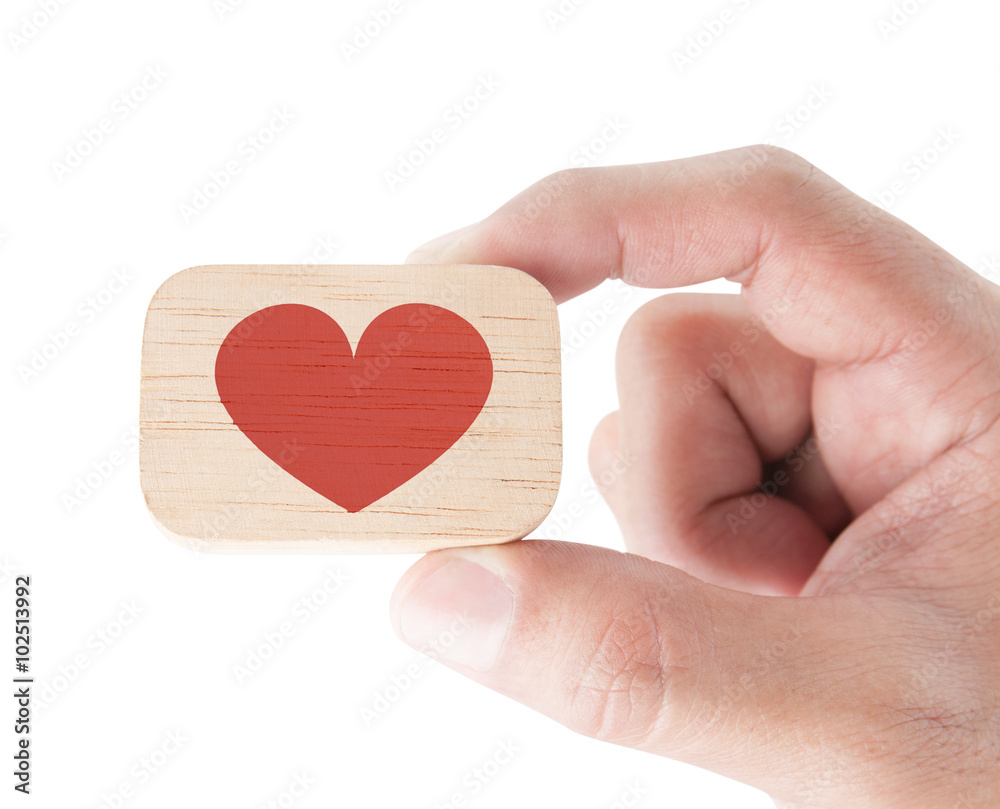 Hand holding a wooden block and red heart on white background