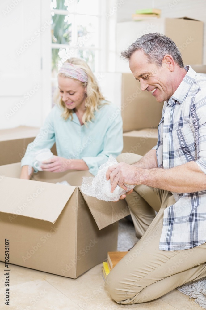 Smiling couple packing mug in a box Smiling couple packing mug in a box