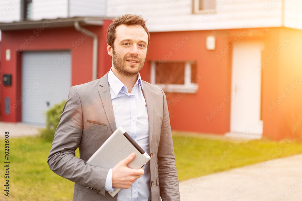 Portrait of a young real estate agent in front of a house - obrazy, fototapety, plakaty 