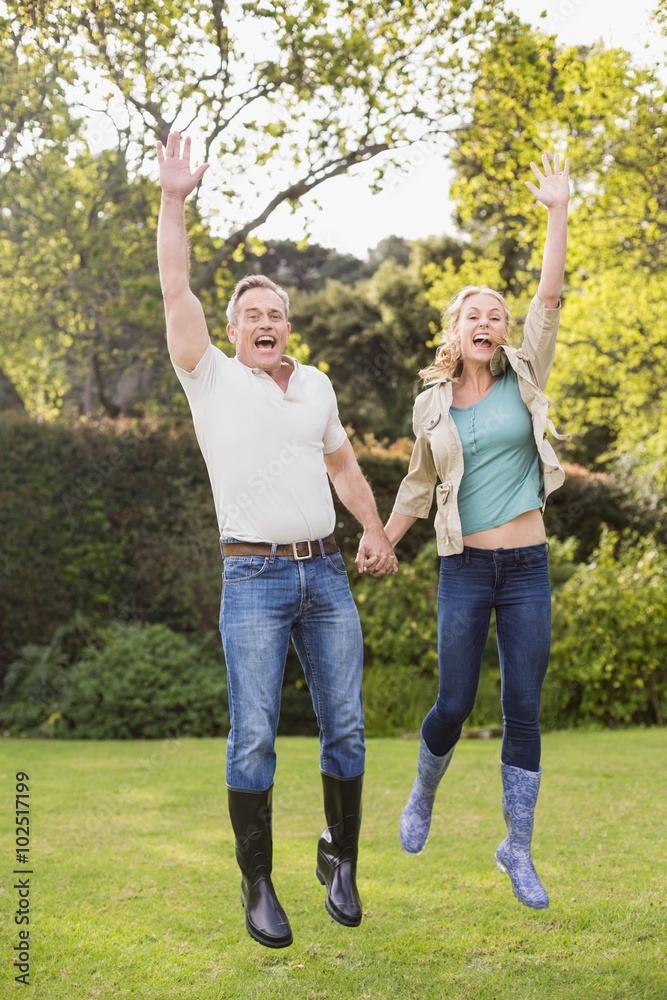 Fototapeta premium Cute couple jumping with arms in the air