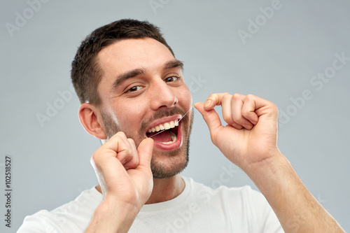 Quadro em tela man with dental floss cleaning teeth over gray