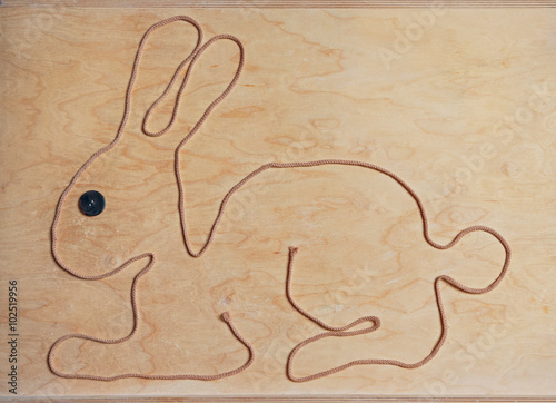 Osterhase aus einer Schnur geformt, mit Holz-Hintergrund