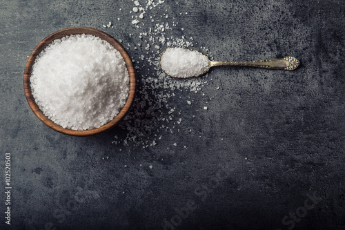 Salt. Coarse grained sea salt on granite - concrete  stone background with vintage spoon and woden bowl. photo