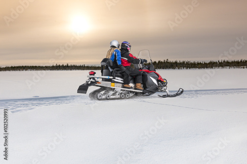 Couple driving snowmobile on snow 
