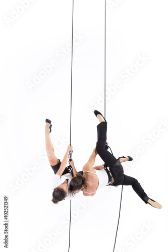 Two girls dressed executive with harnesses hanging from a climbing rope