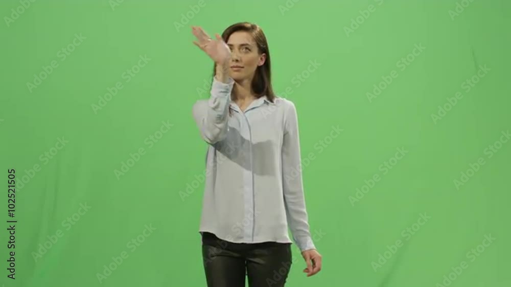 Woman is working with a virtual interactive interface on a mock-up green screen in the background. Shot on RED Cinema Camera. Woman is working with a virtual interactive interface on a mock-up green screen in the background. Shot on RED Cinema Camera.