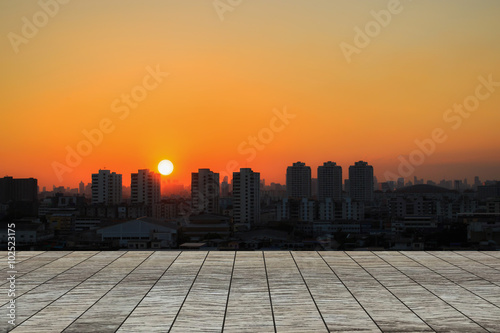 Wood table top on Sunset in the city background