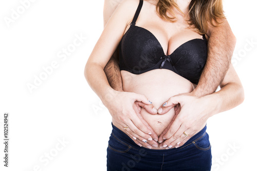 hands of pregnant woman and her husband in heart shape on her be