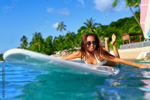 Summer Adventure. Water Sports. Happy Carefree Sexy Woman In Bikini Surfing, Lying On Paddle, Surf Board In Sea At Exotic Resort. Holidays Travel Vacation. Healthy Active Lifestyle. Leisure Activity. 